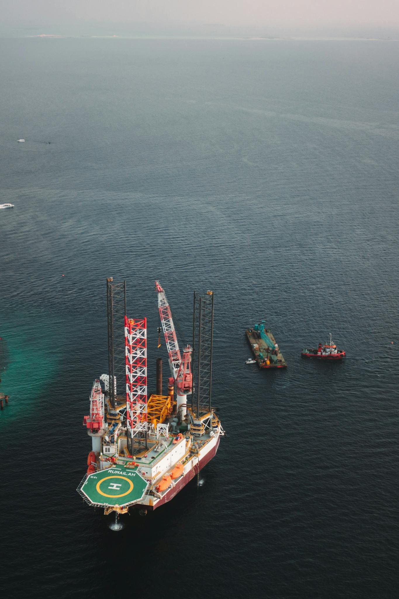 Aerial view of an offshore oil platform with support vessels in the open sea, showcasing industrial maritime infrastructure.